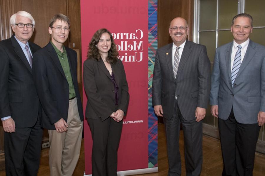 A photo of five people standing in front of a CMU sign. To the left of the sign are two men in suits, the one on the right being Farnam Jahanian. In front of and to the right of the sign are three formally dressed professors