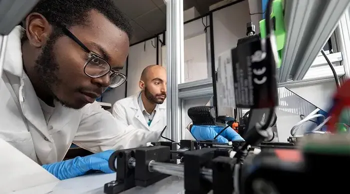 Two Carnegie Mellon students in a laboratory with a microscope.